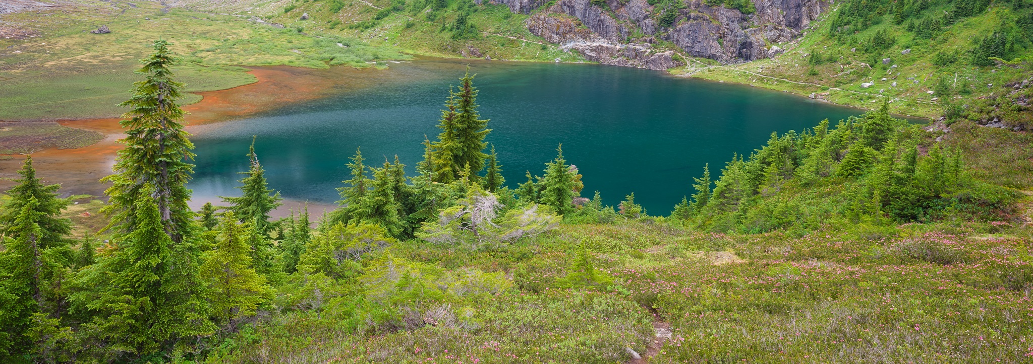A pristine alpine lake reflects the mountain sky on a clear summer evening, Washington. Photograph by Marty Quinn