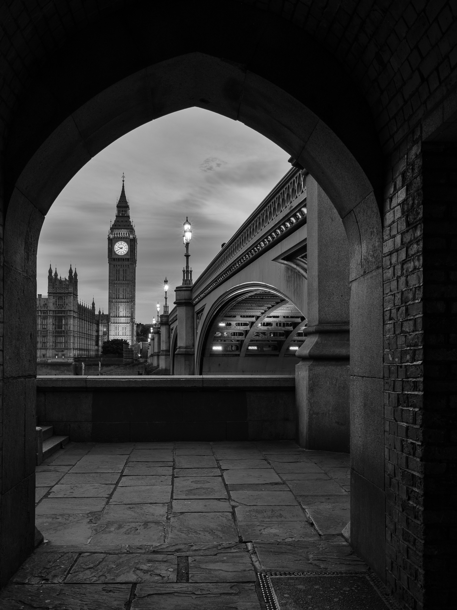 Big Ben and the Houses of Parliament framed through a stone archway near Westminster Bridge, London, at night, International. Photograph by Marty Quinn