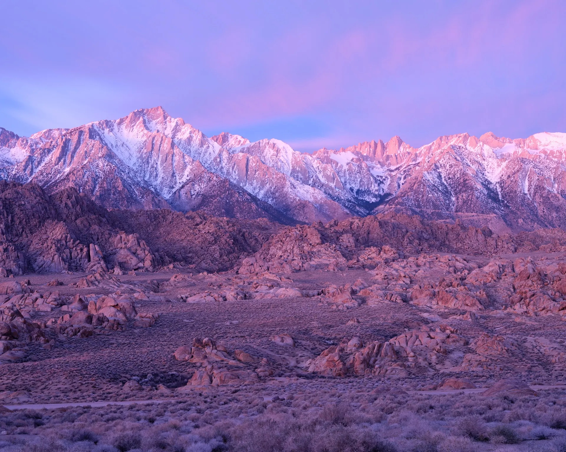 The Sierra Nevada at blue hour before a winter sunrise — the snow-capped peaks dark against a sky that has just started to turn, California. Photograph by Marty Quinn